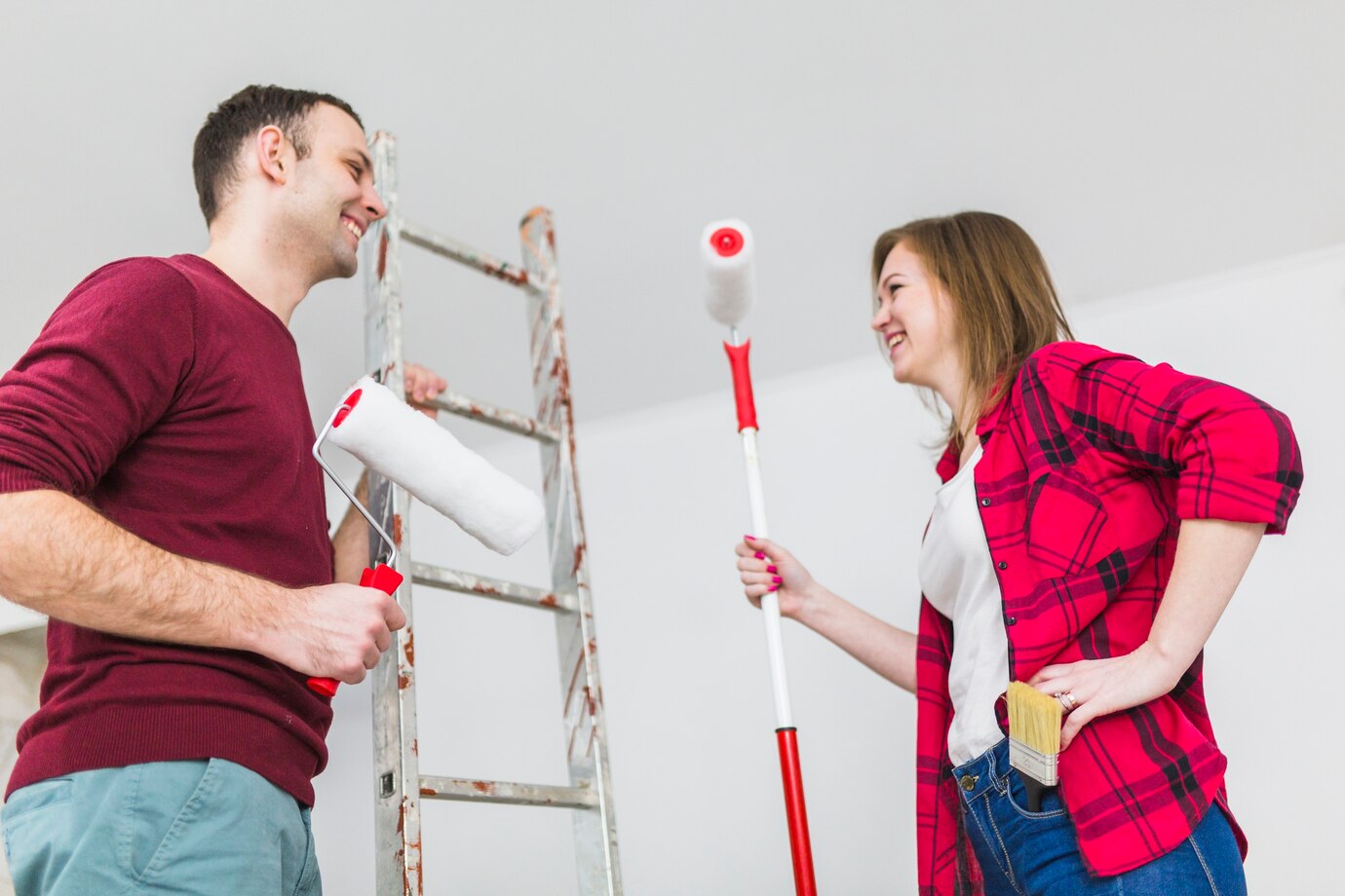 cheerful couple with paint rollers ladder 23 2147782357